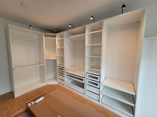 Aufgebautes Kleiderschranksystem mit offenen Fächern, Schubladen und Kleiderstangen in einem leeren Zimmer