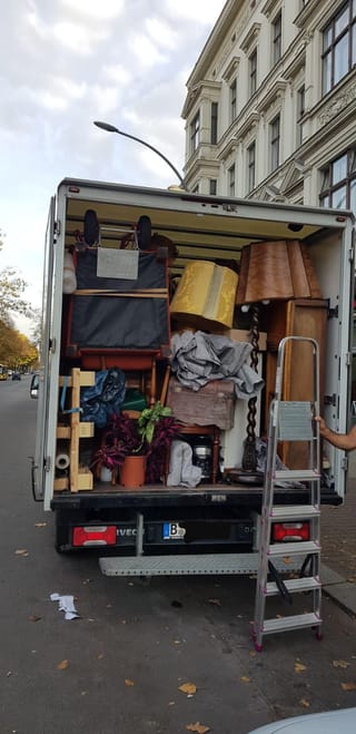 Umzugswagen mit Möbeln, Stehlampen und Pflanzen vor einem Berliner Altbau