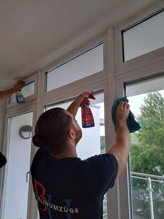 Mitarbeiter von Berlin Umzüge reinigt Fensterscheiben vor der Wohnungsübergabe