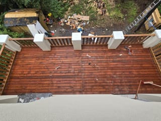 Draufsicht auf eine frisch verlegte und lasierte Holzterrasse mit Holzgeländer